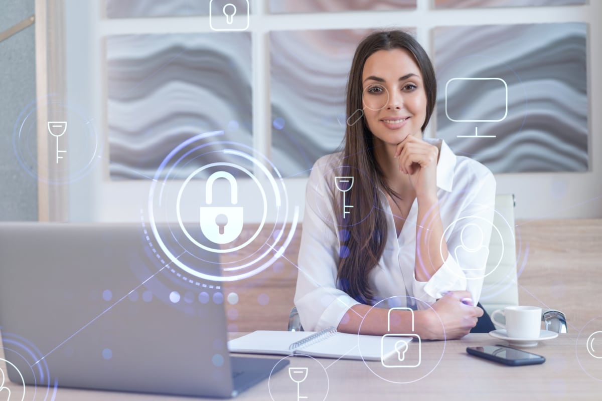 Women smiling in front of a computer with a digital lock representing cybersecurity